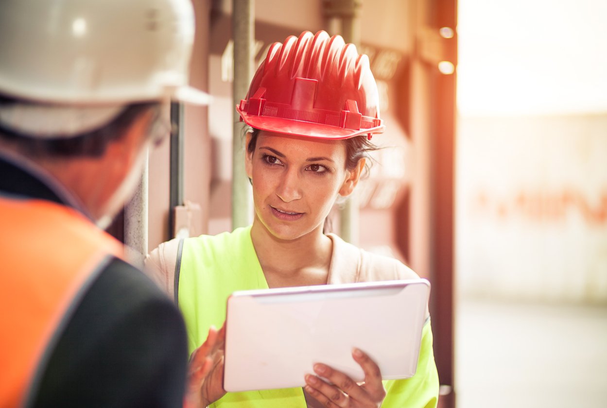 foreman, holding a tablet, talking with a skilled tradesman